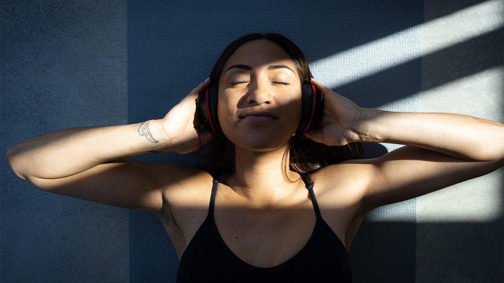 A woman listens to music with headphones looking relaxed